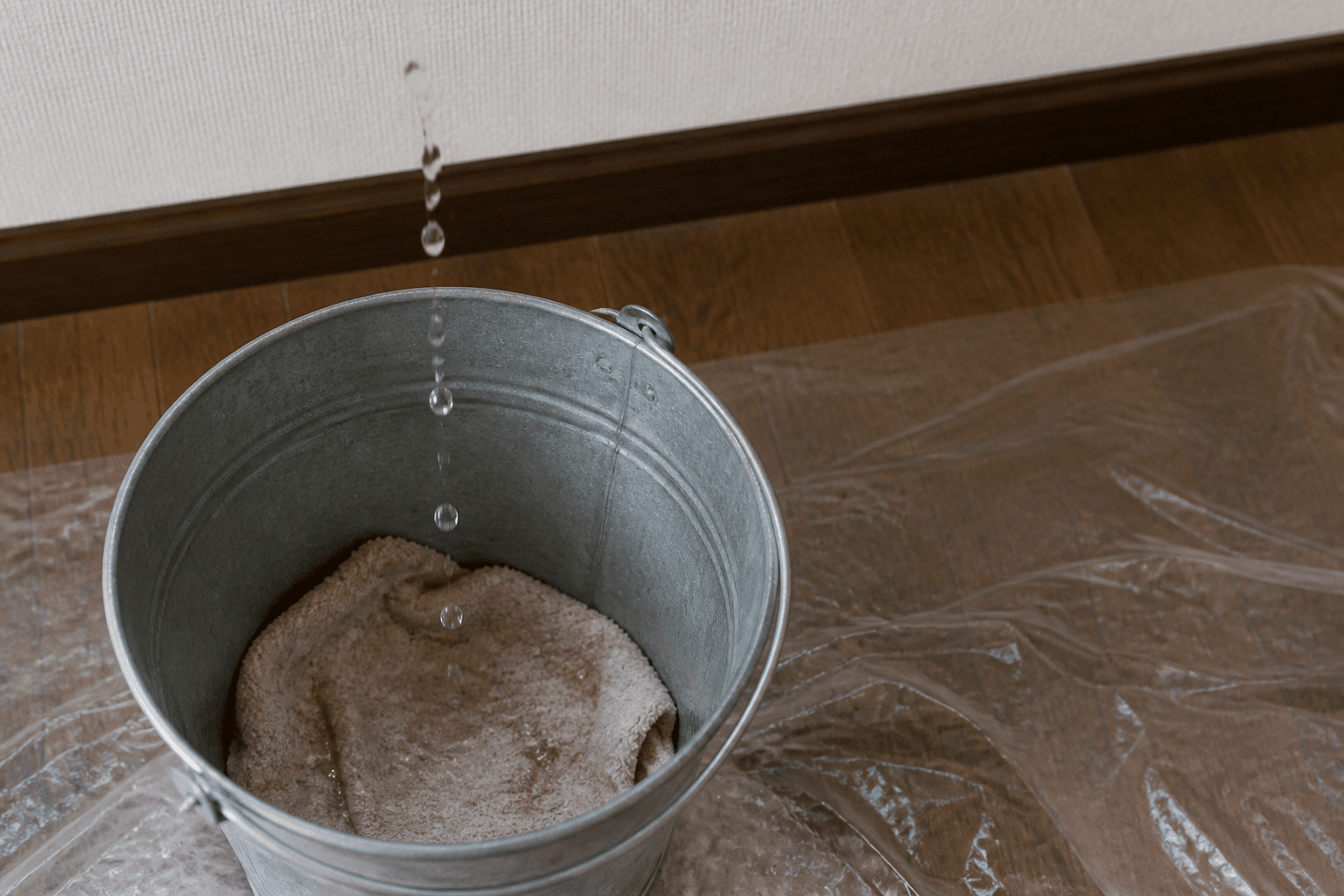 天井から落ちる水滴をバケツで受けている様子の写真。バケツの底に雑巾が敷かれているとより分かりやすい。]